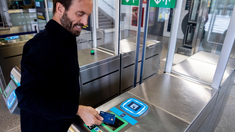 Man tapping his Visa card in public transport turnstile